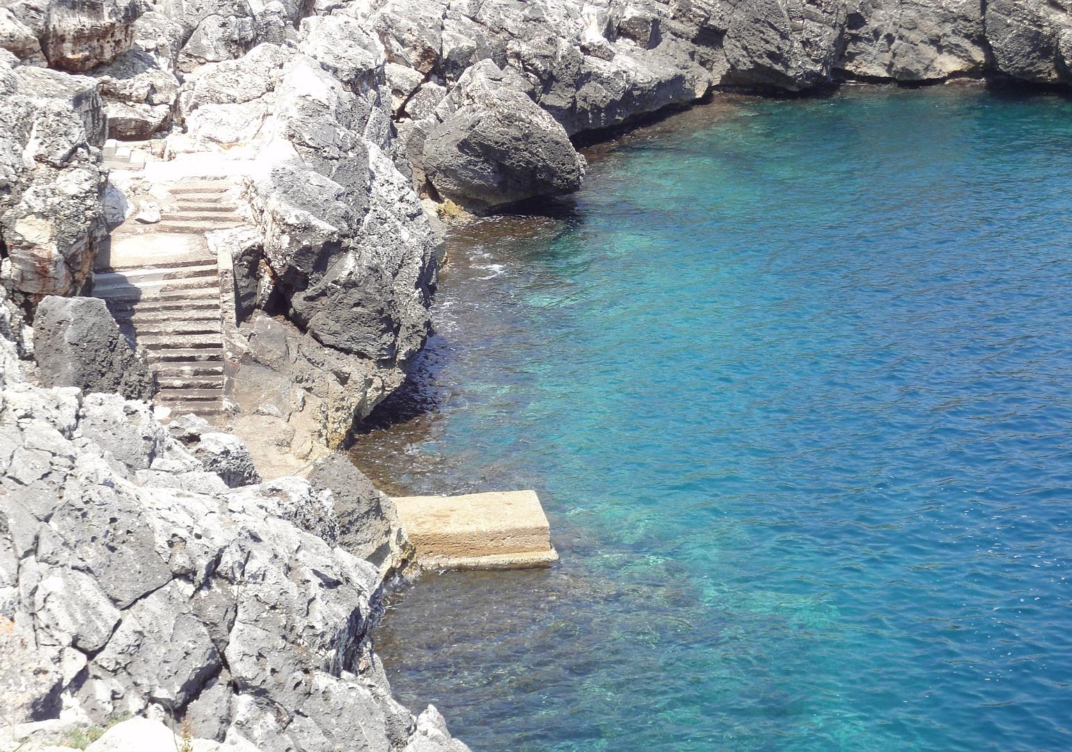 Mer Confortable crique rocheuse privée avec la plate-forme et les escaliers pour entrer dans l‘eau