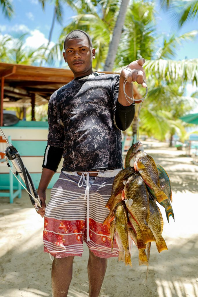 uomo e pesce appena pescato su una costa - fish street food